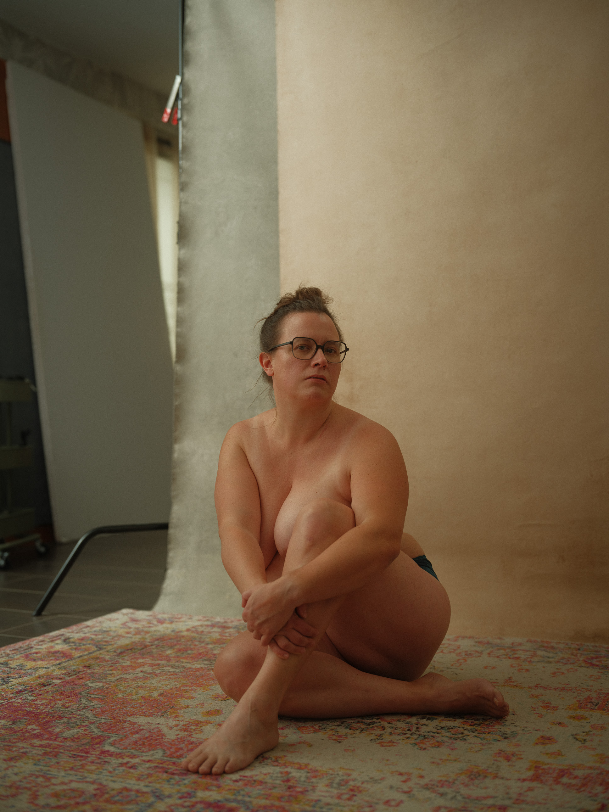 Astrid am Boden sitzend, oben ohne ihre Brust verdeckend